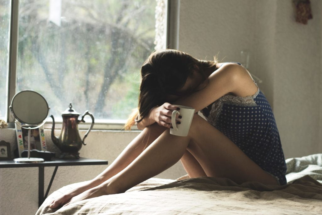 Photo of woman looking down with her head in her arms in despair or depression