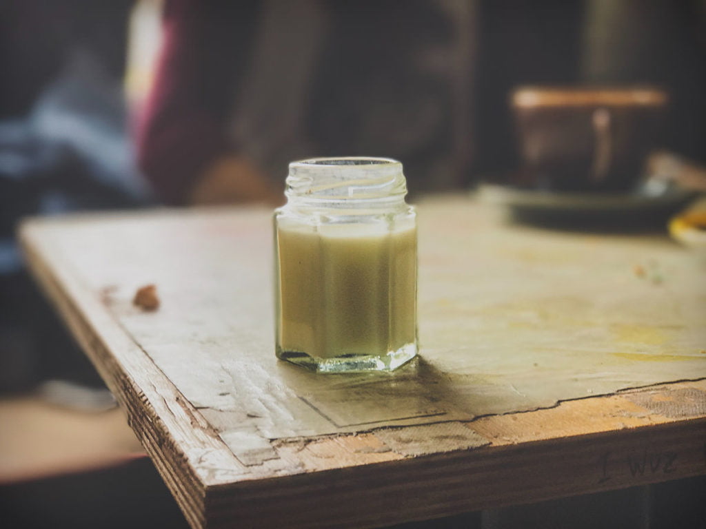Image of a jar of probiotic kefir on a wooden table with light coming in from a window
