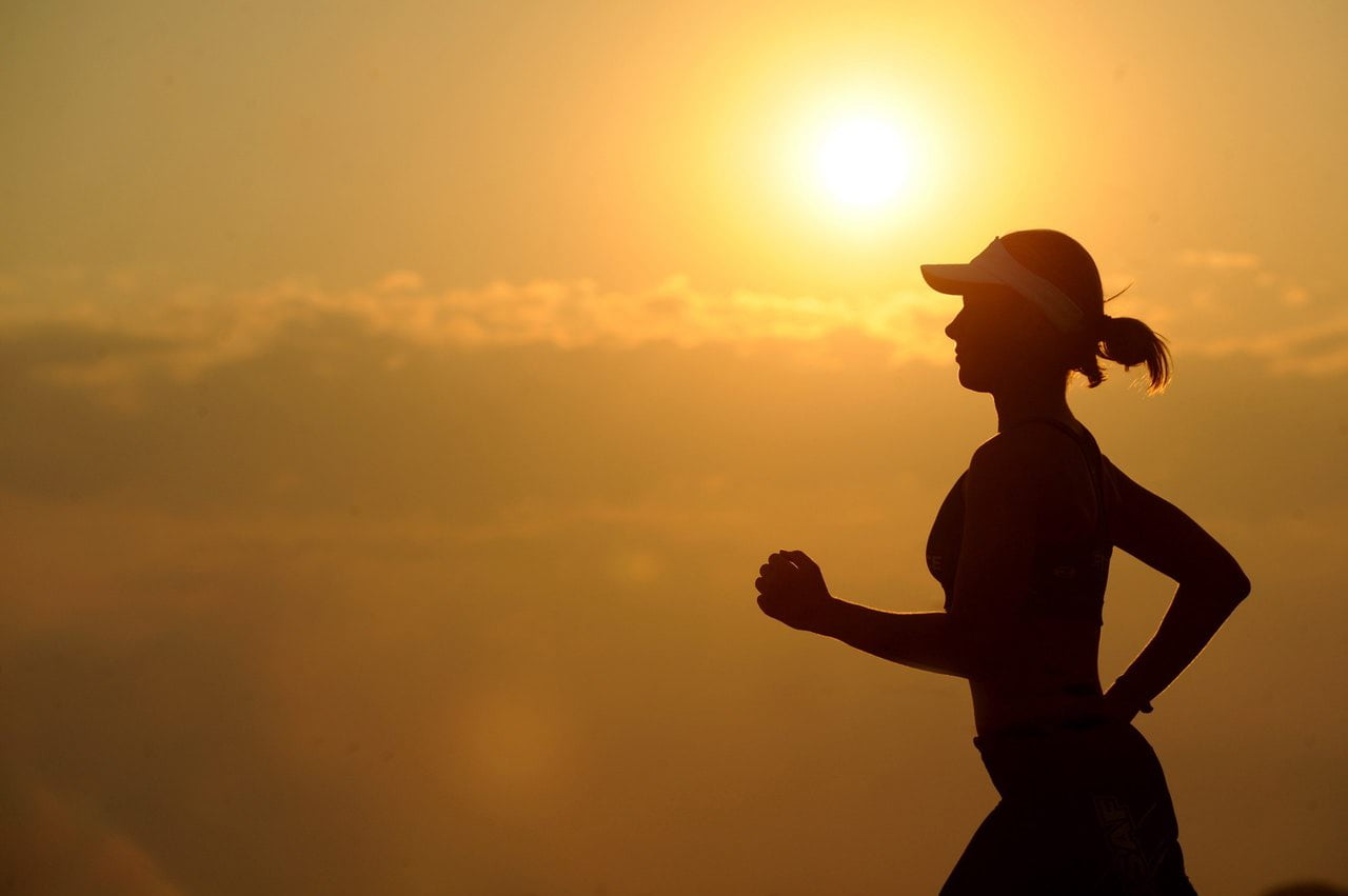 Image of a woman running in front of the sun setting