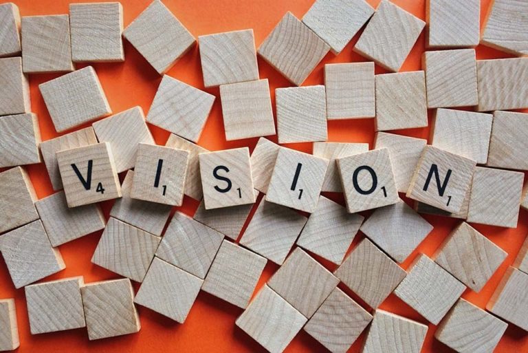 Image of wood blocks against an orange background that spells out 'vision'