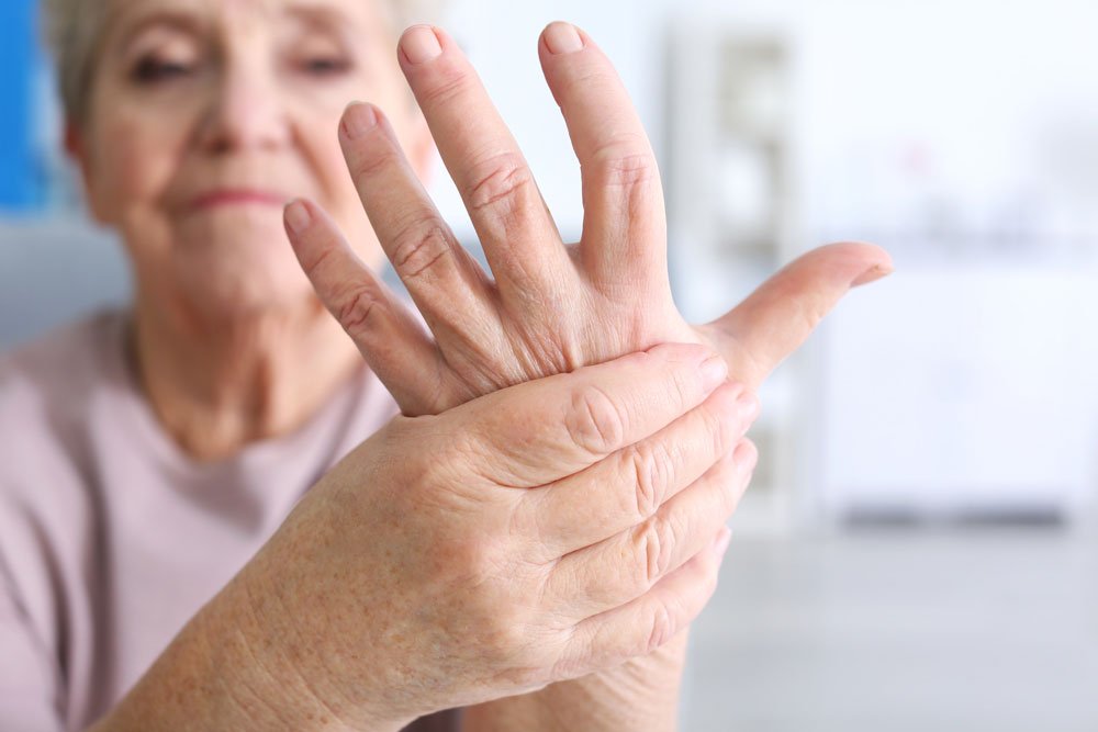 Image of a senior woman holding her hand with arthritis pain